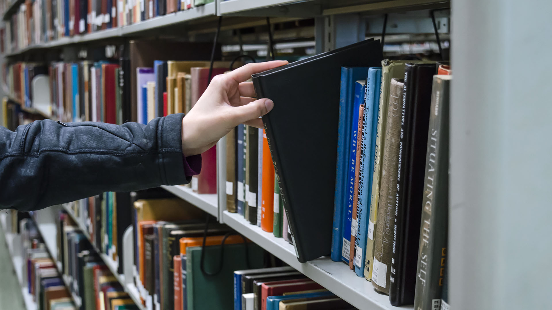 picture of a book being pulled off a library shelf