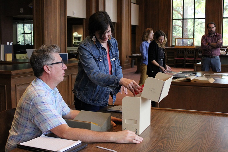 a woman pulls a book from a box while a man observes