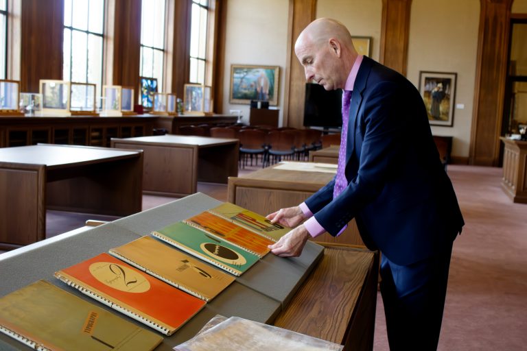 A man touches a row of books on a table