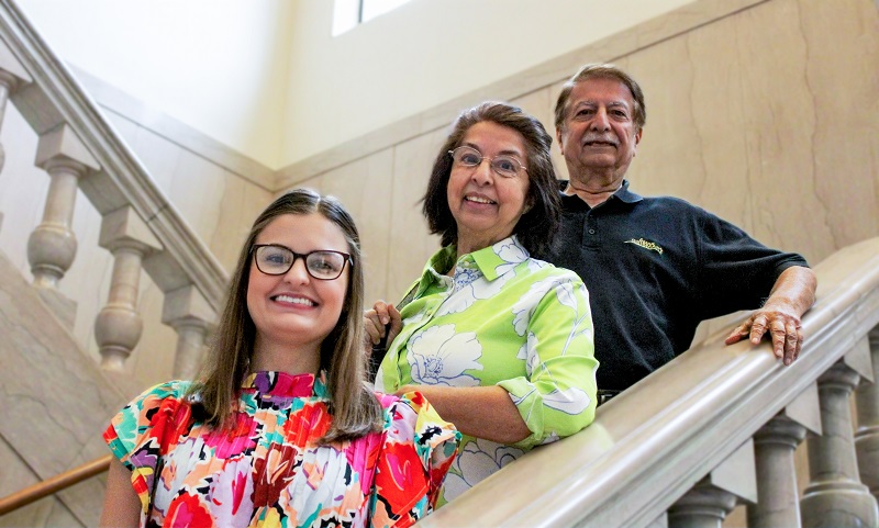 three people pose on a marble staircase