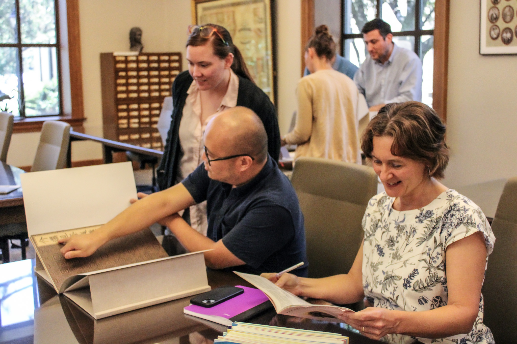 A group of people pore over books and magazines in Hill Memorial Library's Reading Room