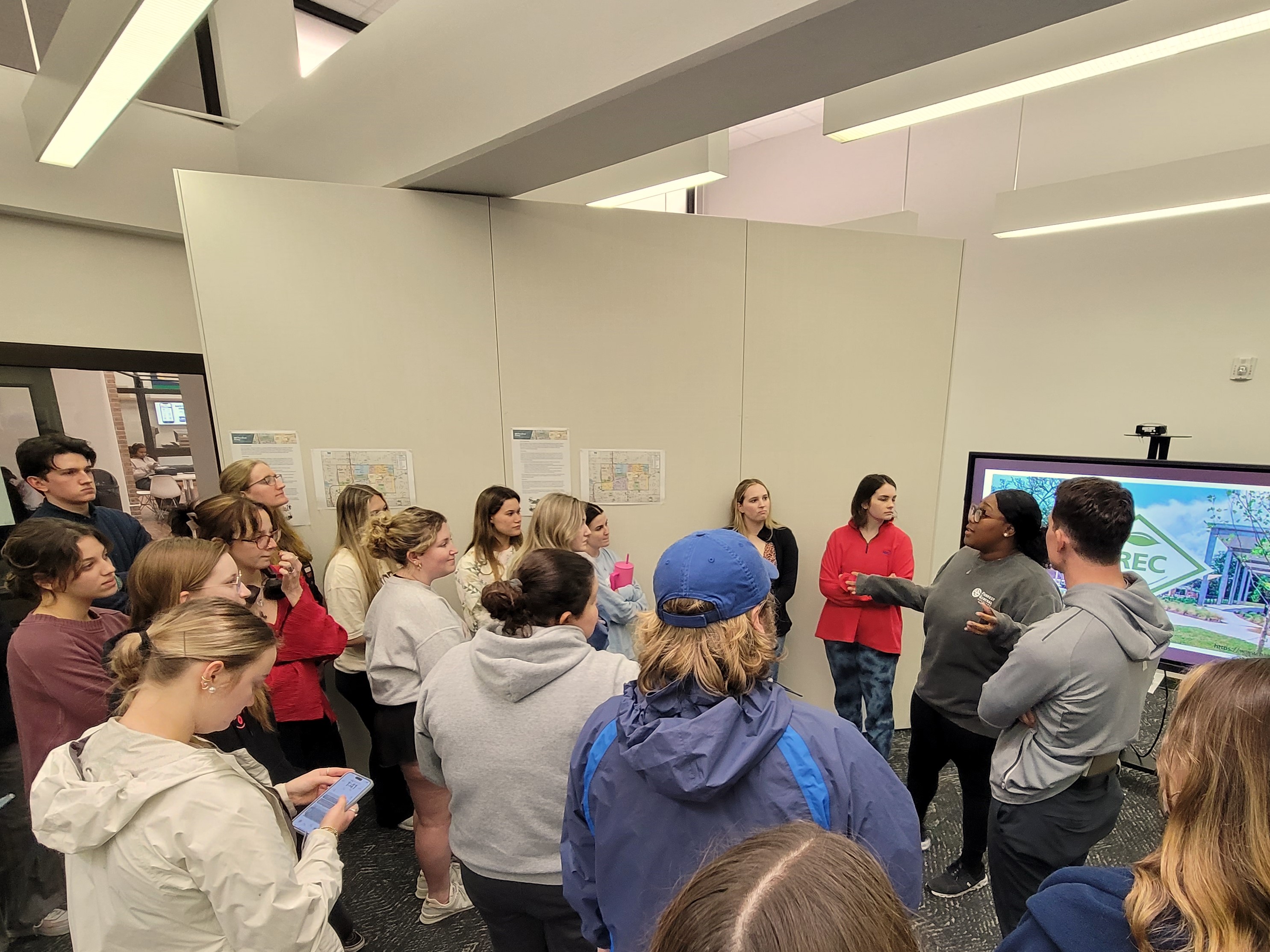 a large class gathers around a TV screen