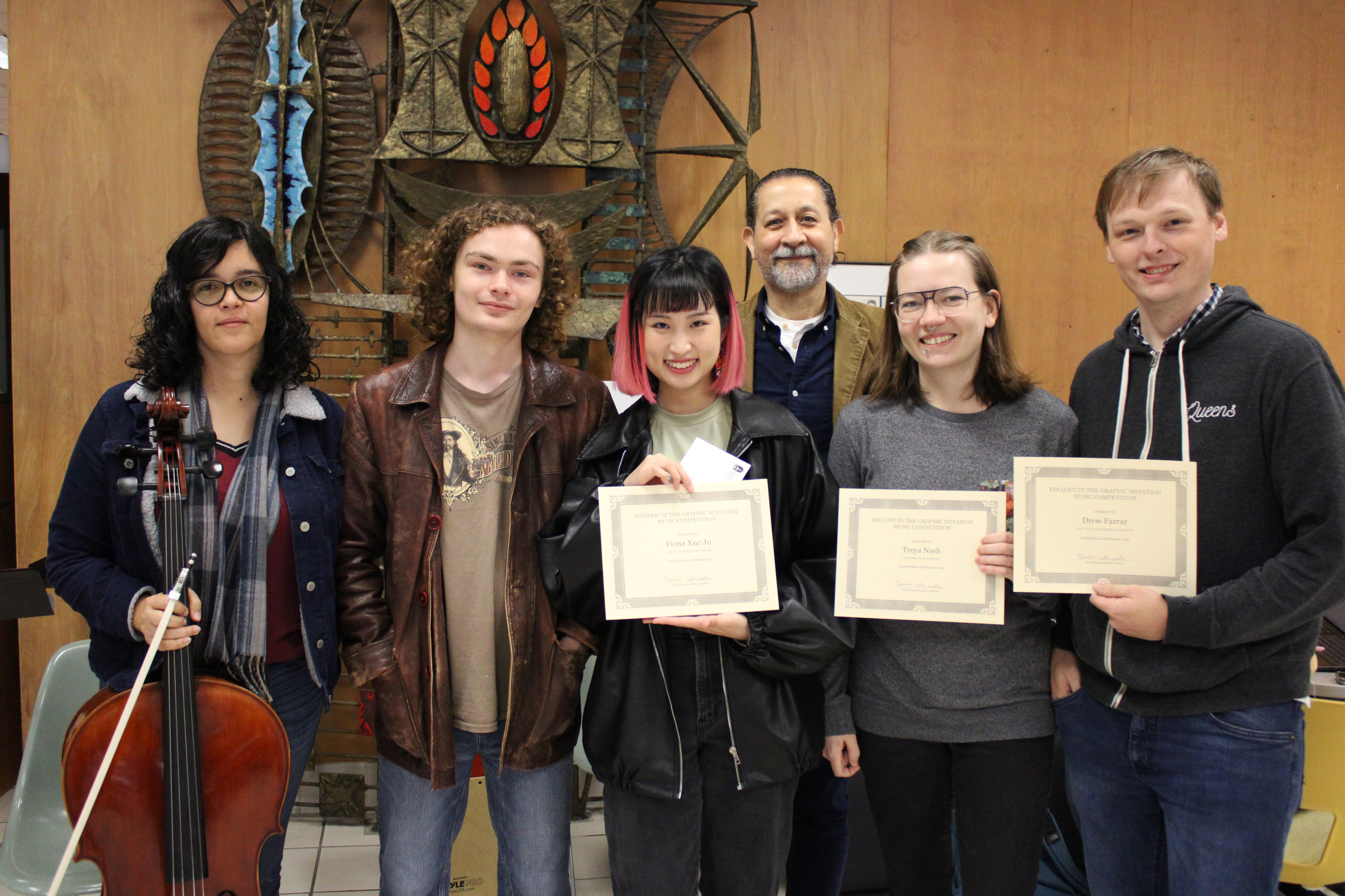 six people pose with certificates and music instruments