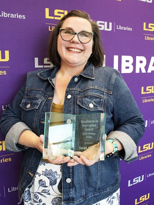 a woman poses with a glass award indoors