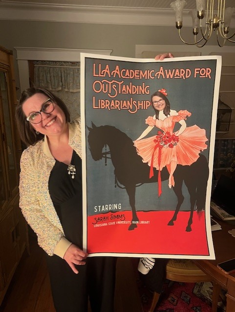 Sarah Simms holds up a poster that reads LLA Academic Award for Outstanding Librarianship